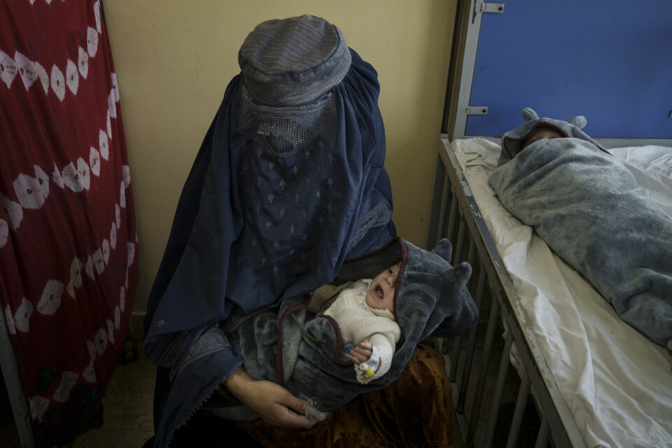 DE SMÅ: En mor holder den ene av de små barna som får behandling i Kabul for underernæring. Flere småbarn blir behandlet ved sykehuset for underernæring og sykdom. A woman holds one of her two babies undergoing treatment at the malnutrition ward of the Indira Gandhi Children's Hospital in Kabul, Afghanistan, Tuesday, Oct. 5, 2021. Health workers in the hospital dashed back and forth caring for gasping premature newborns and others suffering from severe malnutrition and other diseases. (AP Photo/Felipe Dana)