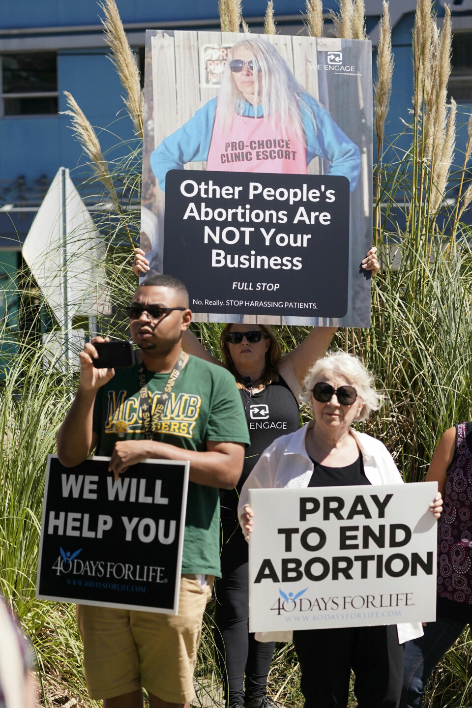 PROTEST: Abortmotstandere og tilhengere utenfor klinikken i Jackson. A clinic escort holds an abortion rights poster featuring clinic escort Derenda Hancock as a anti-abortion protest takes place outside the Jackson Women's Health Organization clinic in Jackson, Miss., Wednesday, Sept. 22, 2021. The clinic is the state's only medical facility able to provide abortions on demand. Anti-abortion advocates gathered outside the clinic and gave prayerful support to their cause. (AP Photo/Rogelio V. Solis)