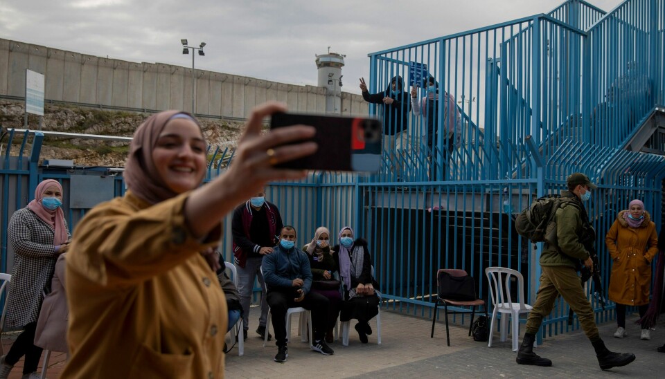 VAKSINERTE: Palestinere tar bilder etter å ha fått koronavaksine fra et israelsk helseteam ved militærposten i Qalandia på den okkuperte Vestbredden i februar. Palestinere tar bilder etter å ha fått koronavaksine fra et israelsk helseteam ved militærposten i Qalandia på den okkuperte Vestbredden i februar. Arkivfoto: Oded Balilty / AP / NTB