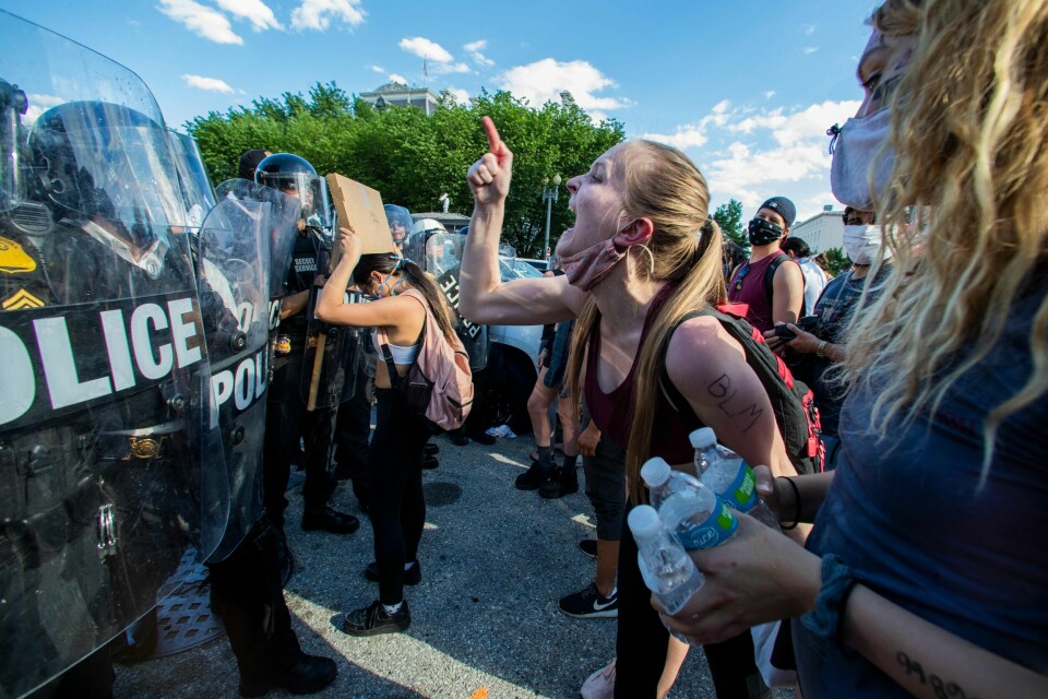 Demonstranter roper mot politi med opprørsutstyr i en protest mot drapet på George Floyd den 30. mai 2020. Politiet har satt opp sperrer for å hindre demonstrantene å komme nær Det hvite hus. (AP Photo/Manuel Balce Ceneta).