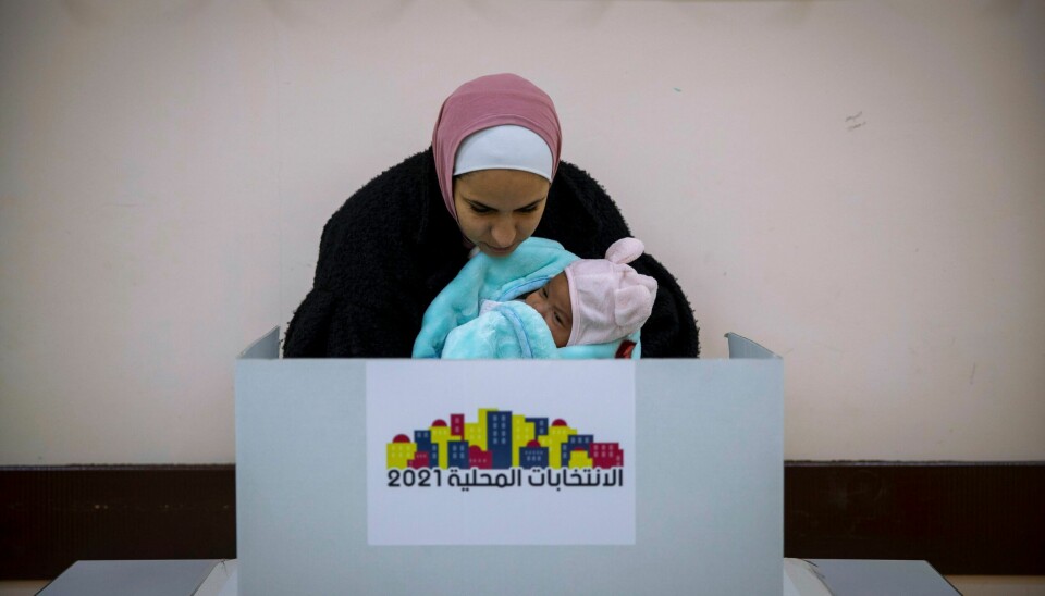 STEMMER: En palestinsk kvinne holder en baby mens hun avlegger sin stemme under lørdagens lokalvalg på Vestbredden. Foto: Majdi Mohammed / AP / NTB En palestinsk kvinne holder en baby mens hun avlegger sin stemme under lørdagens lokalvalg på Vestbredden. Foto: Majdi Mohammed / AP / NTB