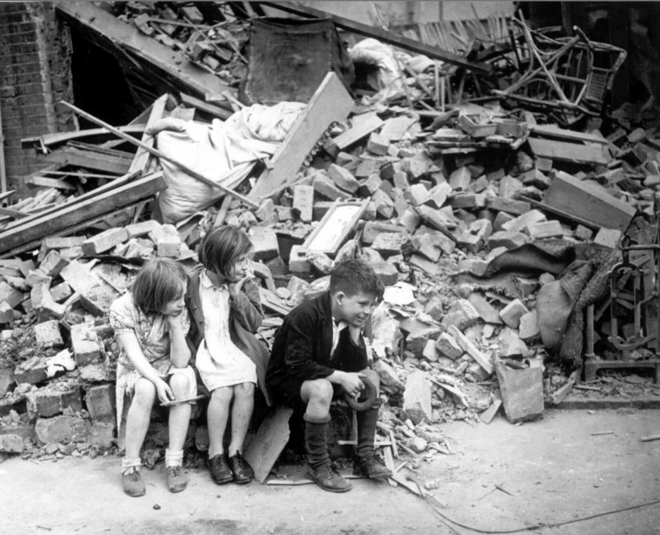 Etter enda en natt med tysk bombing i september 1940, sitter tre barn ved det som en gang var hjemmet deres i Øst-London. Foto: AP/NTB