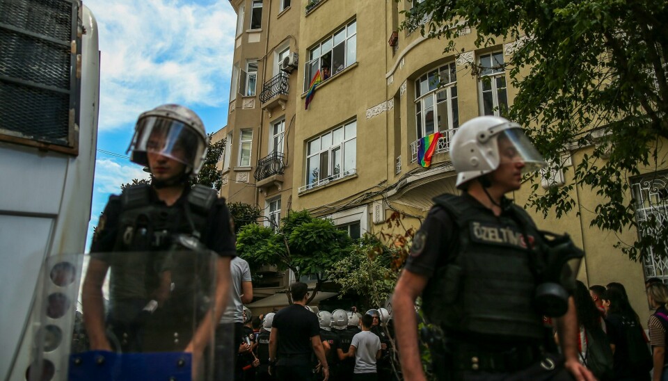 Folk viser fram regnbueflagg mens tyrkiske politimenn sperrer av et område under en pride-markering i Istanbul 26. juni. Minst 150 personer ble pågrepet under en Pride-markering i Istanbul søndag. Foto: Emrah Gurel / AP / NTB