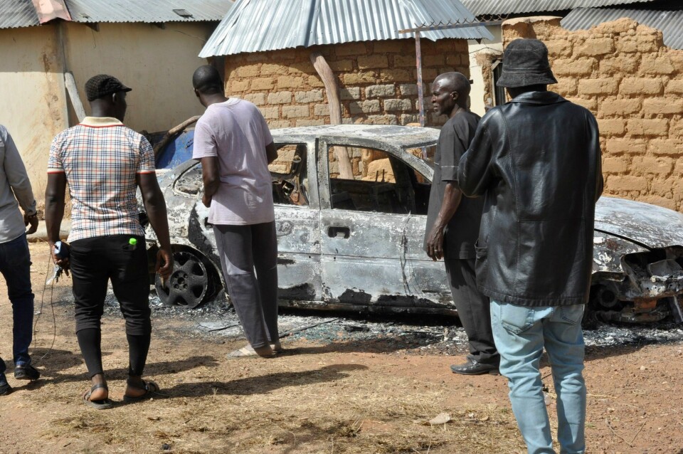 NIGERIA: Lokalbefolkning i Bokkos, sentralt i Nigeria, står rundt en utbrent bil etter at byen ble angrepet av militante gjenger. Landet er delt mellom de kristne i sør og muslimer i nord. People stand by a burnt out car following an attacked by gunmen in Bokkos, north central Nigeria, Tuesday, Dec. 26, 2023.