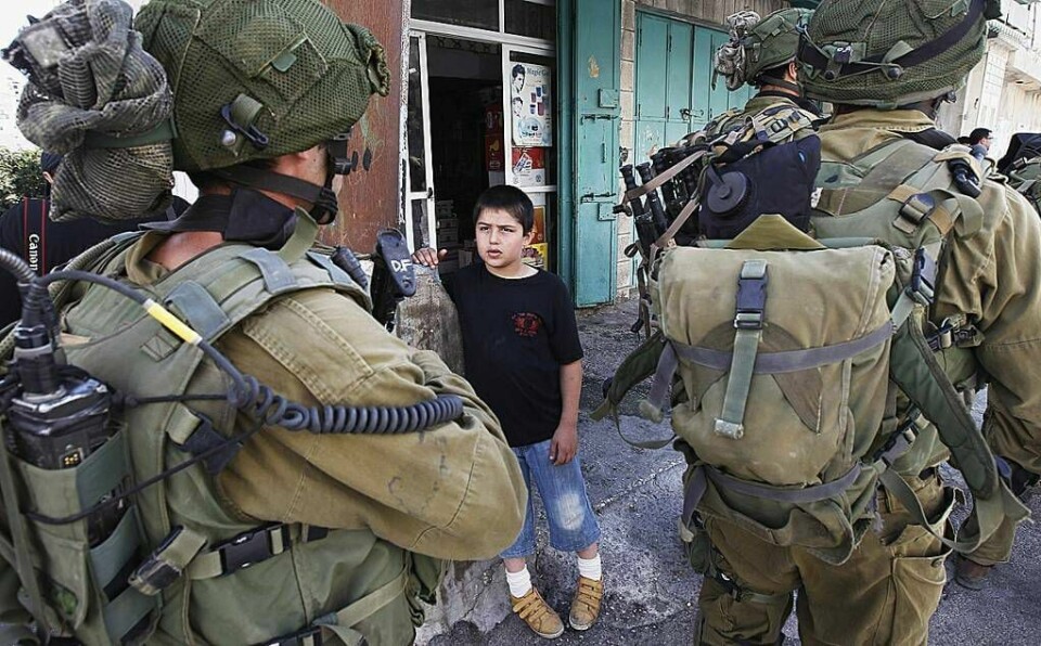 En palestinsk gutt ser på israelske soldater på jakt etter palestinske skyttere i september.