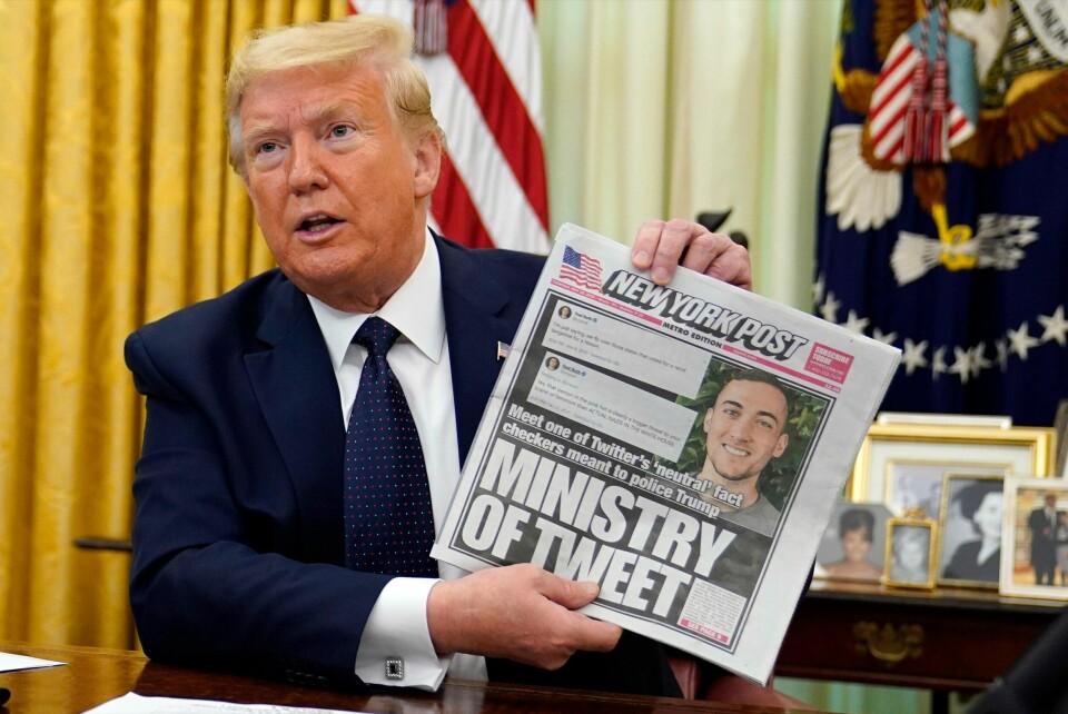 President Donald Trump viser frem et eksemplar av New York Post før han signerer en presidentordre som skal fjerne beskyttelser for sosiale medier-giganter. (AP Photo/Evan Vucci)