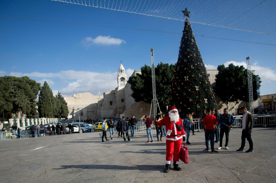En palestinsk mann i julenissekostyme ønsker folk velkommen utenfor Fødselskirken i Betlehem, stedet der kristne tror at Jesus ble født.