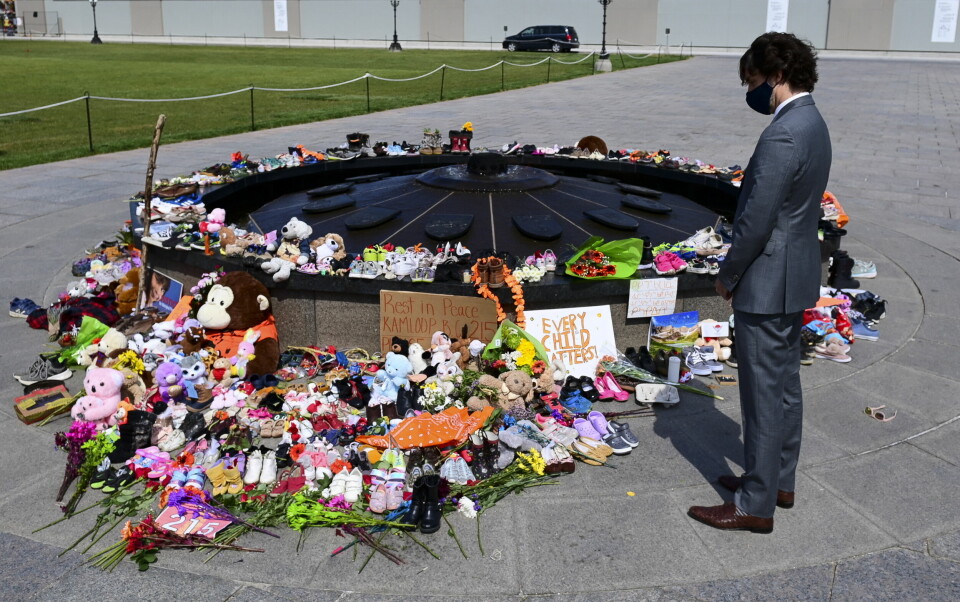 Her legger Canadas statsminister Justin Trudeau ned blomster utenfor nasjonalforsamlingen for å minne de 215 urfolksbarna som ble funnet i umerkede graver ved en tidligere skole. Canadas statsminister Justin Trudeau la tirsdag ned blomster til minne om de mange døde barna som er funnet i en massegrav ved en internatskole for urfolksbarn. Foto: AP / NTB