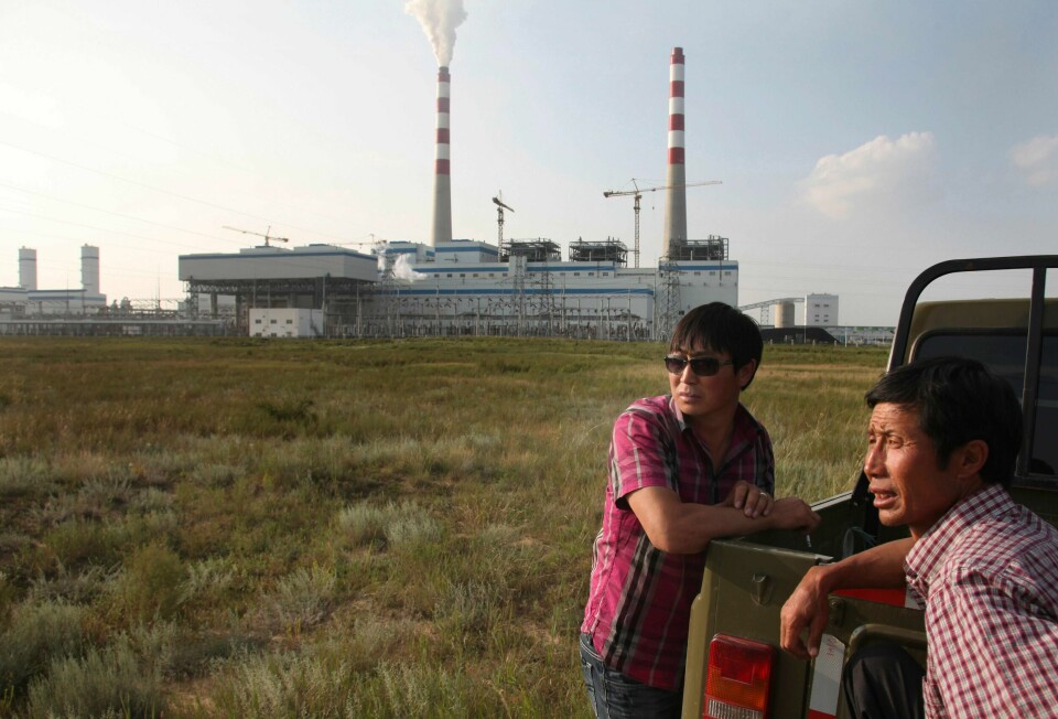 To kinesiske bønder står foran et kullkraftverk i Indre Mongolia, en av provinsene i Kina som bygger ut mest kull for tiden, ifølge en ny rapport fra Global Energy Monitor.