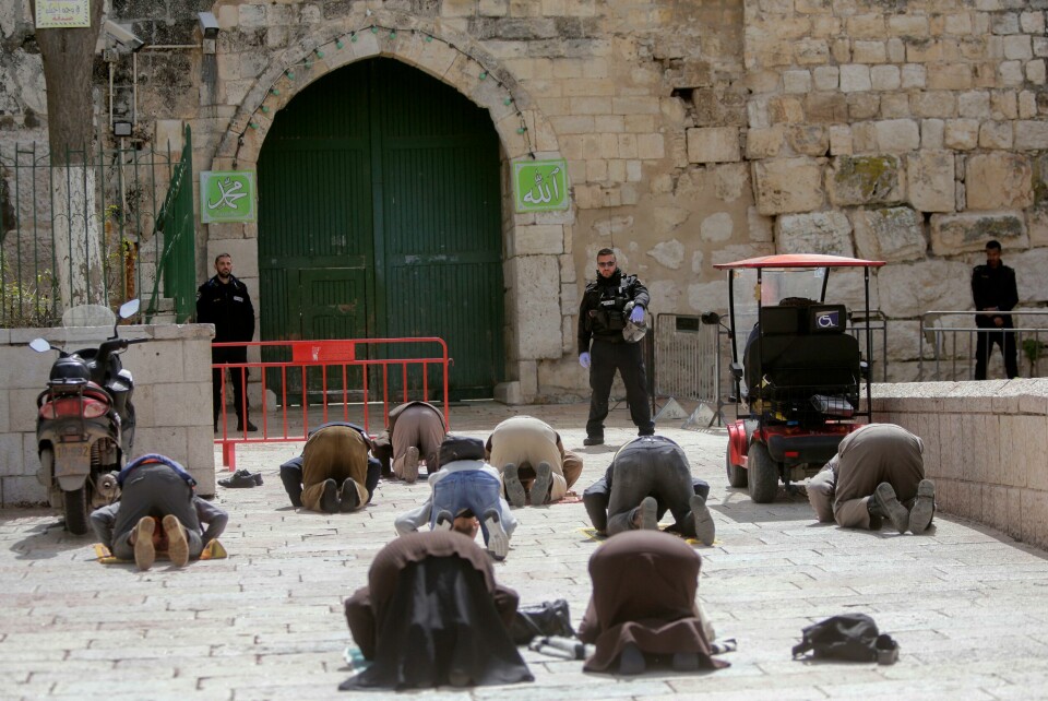 Muslimer ber foran den stengte porten til al-Aqsa-moskeen i Jerusalem. Dette bildet er tatt 23. mars. Nå er reglene enda strengere for å møtes. All utendørs bønn er forbudt. People pray in front of the shuttered gates to al-Aqsa mosque compound as all prayers are suspended to prevent the spread of coronavirus in Jerusalem, Monday, March 23, 2020. In Israel daily life has largely shut down with coronavirus cases multiplying greatly over the past week, (AP Photo/Mahmoud Illean)