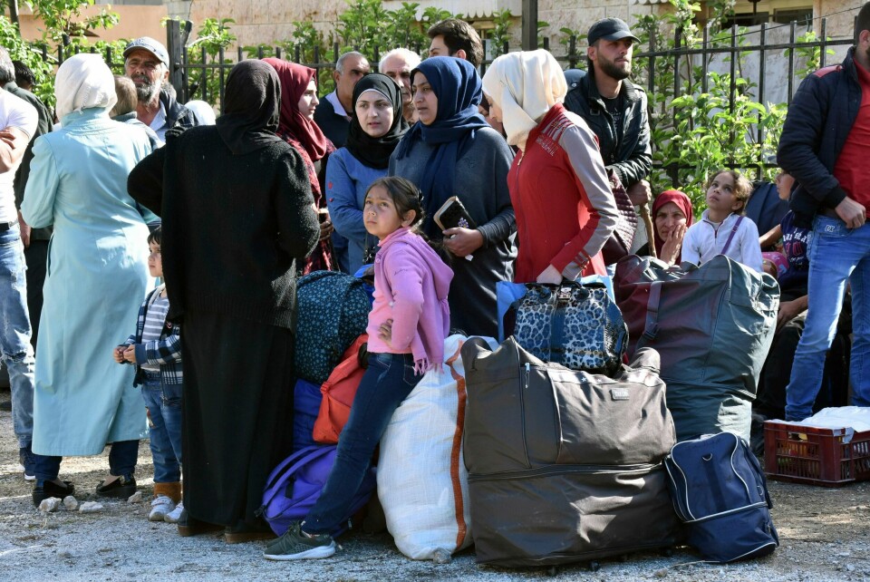 Displaced people who fled the Syrian war stand next to their belongings near the Lebanese-Syrian border as they prepare to return to their village of Beit Jinn in Syria, in the southern village of Shebaa, Lebanon, Wednesday, April, 18, 2018. Hundreds of refugees are headed back to Syria in what they say is a voluntary decision to return to homes in the war-torn country. (AP Photo/Ziad Choufi)