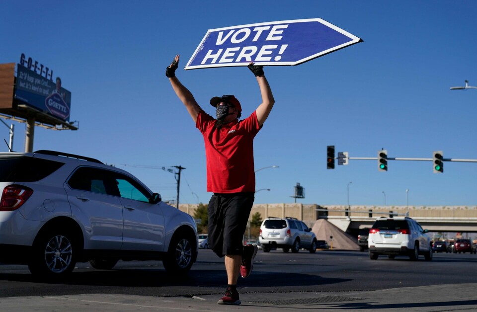 Thomas Salazar holder skiltet med «Vote Here!» utenfor et valglokae i Las Vegas. Forhåndsstemmingen slår alle rekorder.