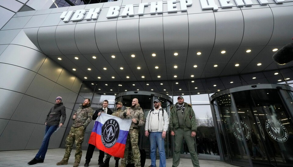 LEIESOLDATER: Disse mennene poserer med Wagner-gruppens logo på det russiske flagget utenfor leiehærens hovedkvarter i St. Petersburg. Trolig er Andrej Medvedev den første avhopperen fra Wagner-gruppen, en privat leiesoldatgruppe i Russland. Foto: AP / NTB