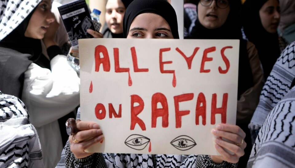 ALLE ØYNE PÅ RAFAH: En demonstrant i Beirut i Libanon holder en plakat til støtte for palestinere på Gazastripen. Fredag ble kontoret til Den internasjonale Røde Kors-komiteen (ICRC) i Gaza rystet av tre eksplosjoner. e