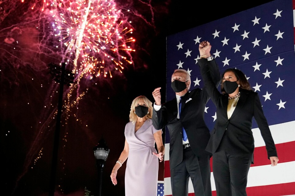 Den demokratiske presidentkandidaten Joe Biden og visepresidentkandidat Kamala Harris holder hender mens de ser på fyrverkeriet som er en markering av at Biden har blitt formelt innsatt som presidentkandidat. Det ble han torsdag 20. august, på den siste dagen på Demokratenes Landsmøte. Til venstre står Biden kone Jill. (AP Photo/Andrew Harnik)
