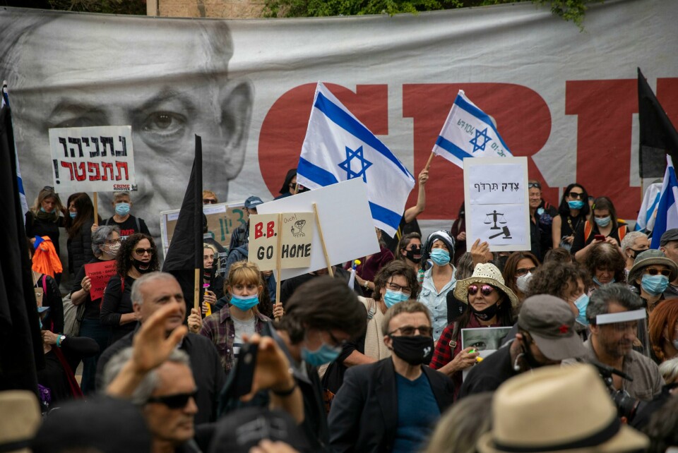 Protester mot Israels statsminister Protesters against Israel's Prime Minister Benjamin Netanyahu wave flags and banners outside his residence in Jerusalem, Sunday, May 24, 2020. Hundreds of protesters calling him the 'crime minister' demonstrated outside his official residence, while hundreds of supporters, including leading members of his Likud party, rallied in support of him at the courthouse. Netanyahu faces charges of fraud, breach of trust, and accepting bribes in a series of corruption cases. The signs say 'Netanyahu resign,' and 'Justice shall you pursue.' (AP Photo/Ariel Schalit)
