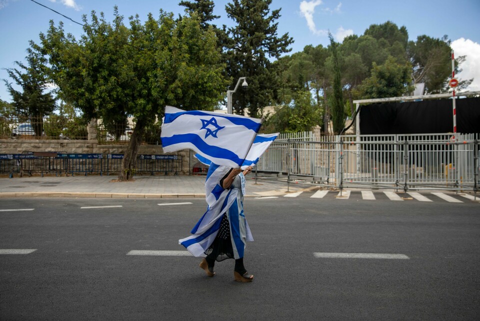 A supporter of Israel's Prime Minister Benjamin Netanyahu waves flags outside his residence in Jerusalem, Sunday, May 24, 2020. Hundreds of protesters calling him the 'crime minister' demonstrated outside his official residence, while hundreds of supporters, including leading members of his Likud party, rallied in support of him at the courthouse. Netanyahu faces charges of fraud, breach of trust, and accepting bribes in a series of corruption cases. (AP Photo/Ariel Schalit) A supporter of Israel's Prime Minister Benjamin Netanyahu waves flags outside his residence in Jerusalem, Sunday, May 24, 2020. Hundreds of protesters calling him the 'crime minister' demonstrated outside his official residence, while hundreds of supporters, including leading members of his Likud party, rallied in support of him at the courthouse. Netanyahu faces charges of fraud, breach of trust, and accepting bribes in a series of corruption cases. (AP Photo/Ariel Schalit)