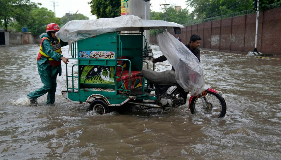 En redningsarbeider hjelper til med å skyve en motorsykkeltaxi mot tørt land i Lahore i Pakistan. En redningsarbeider hjelper til med å skyve en motorsykkeltaxi mot tørt land i Lahore i Pakistan. Foto: K.M. Chaudary / AP / NTB