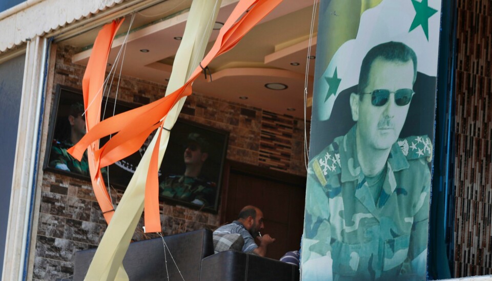 ØDELAGT: Et bilde av Syrias president Bashar Assad er satt opp i et ødelagt vindu i byen Masyaf. Området ble utsatt for kraftige israelske angrep søndag kveld. En observatørgruppe i London melder at en underjordisk rakettfabrikk ble fullstendig ødelagt. En plakat med bilde av Syrias president Basha al-Assad i et ødelagt vindu i byen Masyaf, som natt til mandag ble rammet av et omfattende israelsk angrep. Foto: Omar Sanadiki / AP / NTB