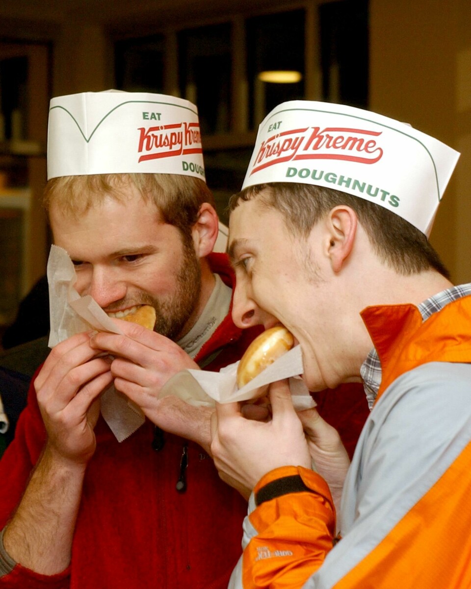 I USA er Krispy Kreme ein nasjonal leverandør av doughnuts - og eigd av familien Reimann. ** ELIMINATES THE REFERENCE TO THE FIRST STORE IN THE STATE ** Dustin Howell, left, and Daniel Geraldson enjoy fresh baked glazed doughnuts before heading to school during the grand opening of Krispy Kreme Doughnuts in Little Rock, Ark., Tuesday, Feb. 17, 2004. The new Little Rock Krispy Kreme, which has the capacity to make over 2,000 doughnuts an hour, is the only one in the state. (AP Photo/Neemah Aaron)