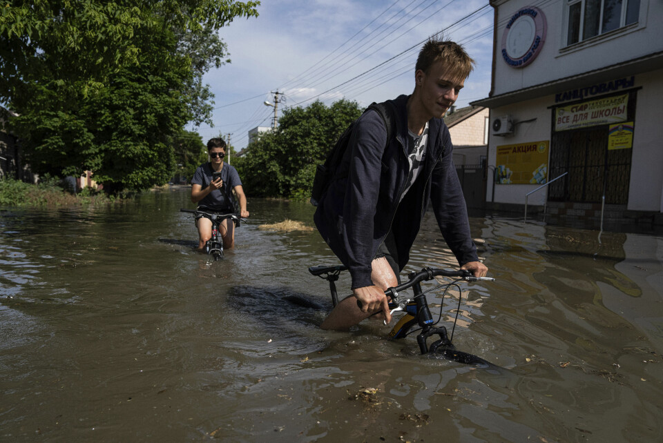 To gutter forsøker å sykle gjennom de store vannmassene i en landsby i Kherson-fylket tirsdag. To gutter forsøker å sykle gjennom de store vannmassene i en landsby i Kherson-fylket tirsdag. Foto: Jevhen Maloletka / AP / NTB