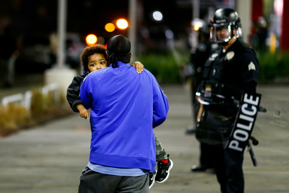 A man holding a child walks by police officers during a protest on election night, Tuesday, Nov. 3, 2020, in Los Angeles. (AP Photo/Ringo H.W. Chiu) A man holding a child walks by police officers during a protest on election night, Tuesday, Nov. 3, 2020, in Los Angeles. (AP Photo/Ringo H.W. Chiu)