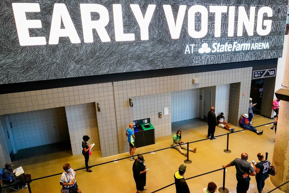 Køer for å stemme på en sportsarena i Atlanta, som er hovedstaden i Georgia. Folk står i kø i mange timer. FILE - In this Oct. 12, 2020, file photo, people wait in line to vote early at the State Farm Arena in Atlanta. A surge in coronavirus cases is hitting key presidential battleground states a little more than two weeks before the November election. Voters in Georgia, Texas and elsewhere encountered hours-long lines that required congregating with hundreds of other people. (AP Photo/Brynn Anderson, File)