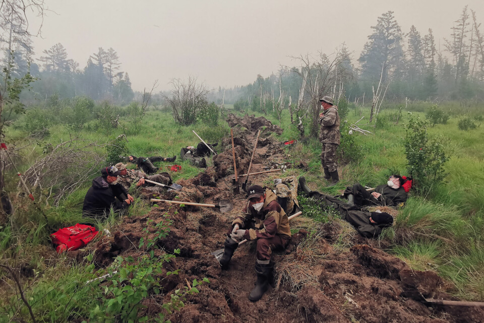 KAMPEN MOT FLAMMENE: Frivillige har forsøkt å grave korridorer for å hindre skogbrannene i å spre seg. Volunteers rest as they dig a moat to stop a forest fire in the republic of Sakha also known as Yakutia, Russia Far East, Saturday, July 17, 2021. Russia has been plagued by widespread forest fires, blamed on unusually high temperatures and the neglect of fire safety rules, with the Sakha-Yakutia region in northeastern Siberia being the worst affected. (AP Photo/Ivan Nikiforov)