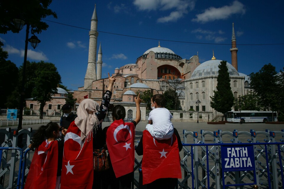 People, draped in Turkish flags stand outside the now closed Byzantine-era Hagia Sophia, one of Istanbul's main tourist attractions in the historic Sultanahmet district of Istanbul, Saturday, July 11, 2020. Turkey's President Recep Tayyip Erdogan formally reconverted Hagia Sophia into a mosque and declared it open for Muslim worship, hours after a high court annulled a 1934 decision that had made the religious landmark a museum.The decision sparked deep dismay among Orthodox Christians. Originally a cathedral, Hagia Sophia was turned into a mosque after Istanbul's conquest by the Ottoman Empire but had been a museum for the last 86 years, drawing millions of tourists annually. (AP Photo/Emrah Gurel) People, draped in Turkish flags stand outside the now closed Byzantine-era Hagia Sophia, one of Istanbul's main tourist attractions in the historic Sultanahmet district of Istanbul, Saturday, July 11, 2020. Turkey's President Recep Tayyip Erdogan formally reconverted Hagia Sophia into a mosque and declared it open for Muslim worship, hours after a high court annulled a 1934 decision that had made the religious landmark a museum.The decision sparked deep dismay among Orthodox Christians. Originally a cathedral, Hagia Sophia was turned into a mosque after Istanbul's conquest by the Ottoman Empire but had been a museum for the last 86 years, drawing millions of tourists annually. (AP Photo/Emrah Gurel)