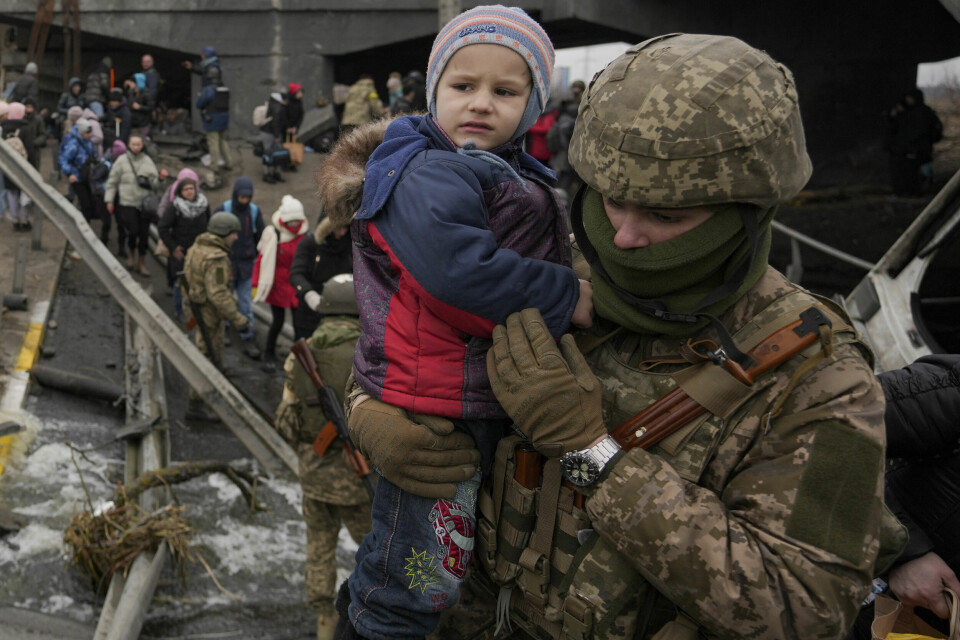 HJELP: Ein ukrainsk soldat ber eit barn over ei bomba bru ved byen Irpin. barn