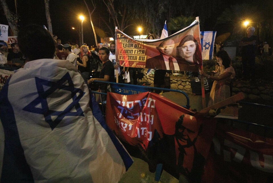 PROTEST: Israelske høyreaktivister med plakater som viser Naftali Bennett og Ayelet Shaked fra partiet Yamina party. Israeli right-wing activists hold signs showing Naftali Bennett and Ayelet Shaked of the Yamina party, during a demonstration against the possibility of forming a new government in Tel Aviv, Israel, Sunday, May 30, 2021. Bennett, leader of the Yamina party and former ally of Prime Minister Benjamin Netanyahu on Sunday said he would seek to form a coalition government with the Israeli leader's opponents, taking a major step toward ending the rule of the longtime premier. (AP Photo/Sebastian Scheiner)