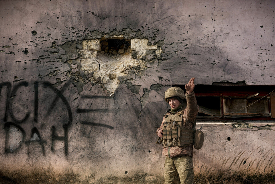 ANGREP: En ukrainsk soldat peker i retningen et granatangrep kom fra ved siden av en bygning i Luhansk som ble truffet lørdag. En ukrainsk soldat viser fram en bygning som ble truffet av et granatangrep nær frontlinjen i Donbass. Foto: Vadim Ghirda / AP / NTB