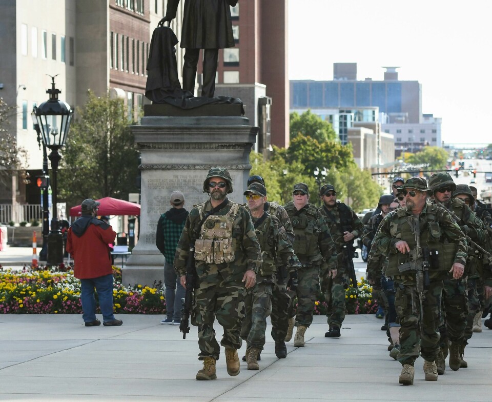Tungt bevæpnede militsgrupper marsjerer i gatene i flere amerikanske byer, som her i Michigan der de i september protesterte mot smitteverntiltak for å hindre spredning av koronavirus. Michigan Home Guard militia members march toward the State Capitol to show their support for gun rights at the Second Amendment March at the State Capitol, Thursday, Sept. 17, 2020, in Lansing, Mich. Dozens gathered on the lawn of the Michigan Capitol to rally in support of their right to bear arms as well as to decry efforts undertaken by the state to rein in the coronavirus pandemic efforts they say infringe upon their freedom. (Matthew Dae Smith/Lansing State Journal via AP)