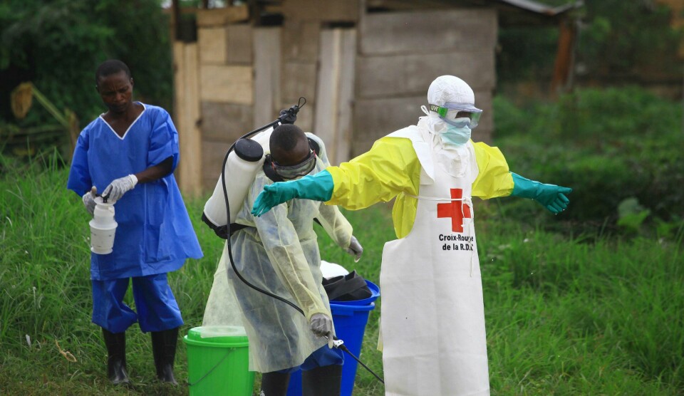 En hjelpearbeider desinfiserer en kollega ved et behandlingssenter mot ebola i Beni. FILE - In this Sunday, Sept 9, 2018 file photo, a health worker sprays disinfectant on his colleague after working at an Ebola treatment centre in Beni, Eastern Congo. The World Health Organization is announcing on Wednesday, Oct. 17 whether Congo's latest outbreak of the deadly Ebola virus should be declared a global health emergency. (AP Photo/Al-hadji Kudra Maliro, file)
